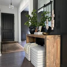 a hallway with black walls and white furniture in the center is decorated with greenery