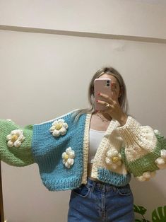 a woman taking a selfie in front of a mirror wearing a sweater with flowers on it