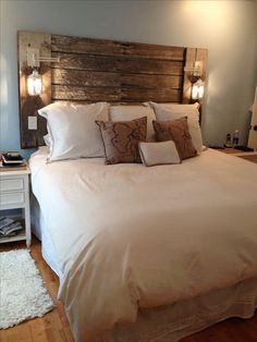 a bed with white sheets and pillows on top of it in a bedroom next to a wooden headboard