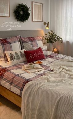 a bed with plaid comforter and pillows in a bedroom next to a wreath on the wall