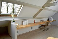 a room with wooden flooring and white walls, has a skylight above the desk