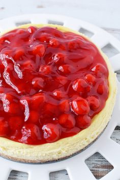 a cheesecake topped with cherries on top of a white plate