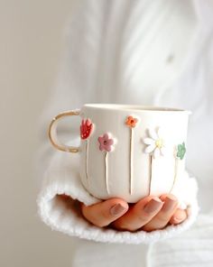 a woman holding a white cup with flowers on it