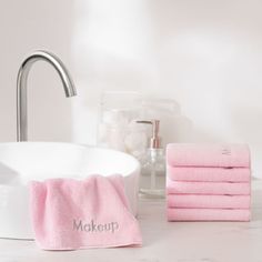 pink towels are stacked next to a white sink