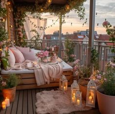 a balcony with lots of potted plants and candles on the floor next to it