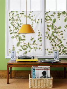 a living room with green walls and white curtains on the window sill, an old record player sits in front of it