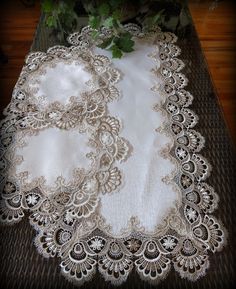 the table cloth has been made with white lace and is on top of a brown mat