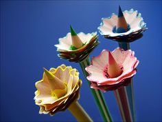 three paper flowers are shown against a blue sky