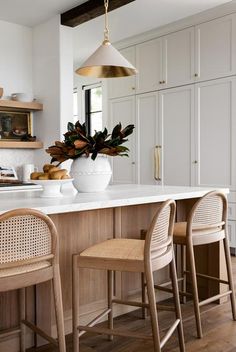 an image of a kitchen setting with white countertops and wooden chairs in the center