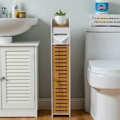 a white toilet sitting next to a wooden cabinet