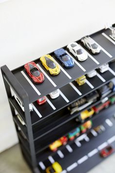 toy cars are lined up on top of each other in a parking garage shelf that is black