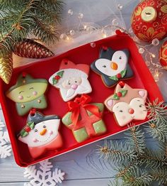 decorated christmas cookies sitting on top of a red tray next to pine cones and ornaments