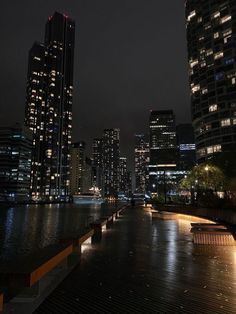 the city skyline is lit up at night with lights reflecting in the water and skyscrapers