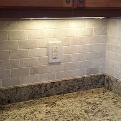 a kitchen counter with a light switch on it's side and marble backsplash