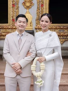 a man and woman standing next to each other in front of a building with gold doors