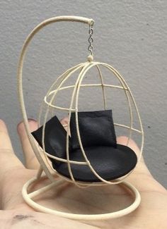 a hand holding a small black object in it's palm, which is shaped like a birdcage