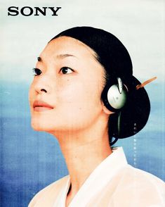 a woman with headphones on her ears looking up at the sky in front of an advertisement for sony