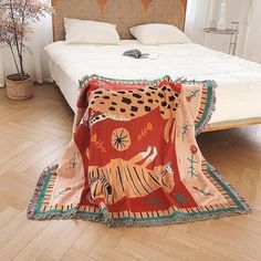 a bed with a blanket on top of it in a bedroom next to a potted plant