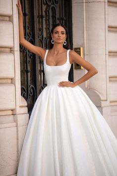 a woman in a white wedding dress posing for the camera with her hand on her hip