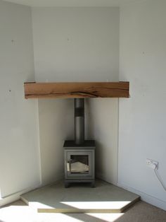 a wood burning stove in the corner of a room with white walls and flooring