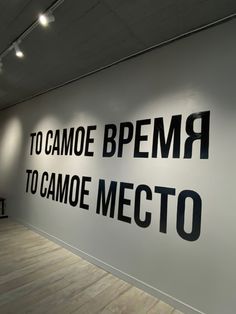 a large white wall with black lettering on it's sides and wooden flooring