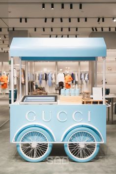 an ice cream cart with wheels on display in a clothing store or retail area,