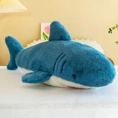 a blue stuffed shark laying on top of a bed