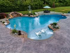 a backyard with a swimming pool, patio and seating area in the middle of it