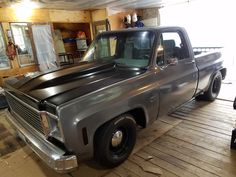 an older pickup truck is parked in a garage with wood flooring and unfinished walls