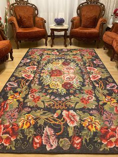 a living room filled with lots of furniture and flowers on the rug in front of two chairs