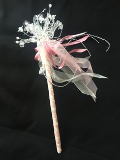 a pink and white candy cane decorated with pearls, ribbons and flowers on a black background