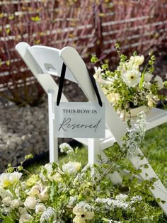 a white chair sitting in the grass next to flowers and a sign that says, this brow is reserved