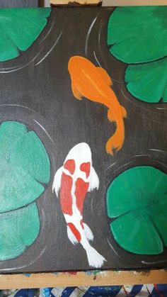 a painting of a koi fish and lily pads on a black background with green leaves