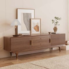 a wooden dresser with two pictures on it and a lamp next to it in a room