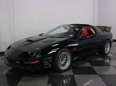 a black sports car parked in a room with a checkered floor and white walls