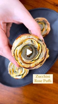 a person is holding a pastry roll on a blue plate with the words zucchini rose puffs