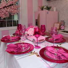 the table is set with pink plates and place settings for two people to sit at