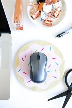 a computer mouse sitting on top of a white plate next to a keyboard and scissors