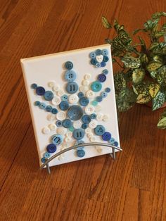 a white tile with blue and white buttons on it next to a potted plant