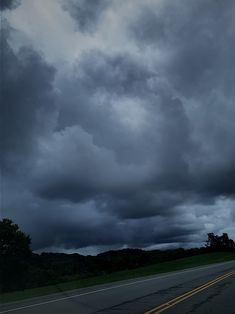 an empty road with dark clouds in the background