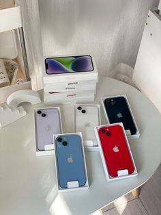 four different colored iphones sitting on top of a white table next to each other