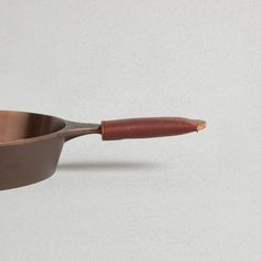 a metal pan with a wooden handle on a white surface