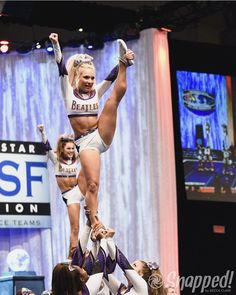 the cheerleaders are doing tricks on the stage for the crowd to see what is happening