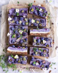 blueberry cheesecake bars on parchment paper with fresh flowers and greenery around them