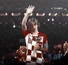 a soccer player waves to the crowd while holding his trophy