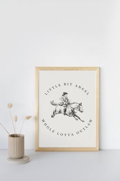 a little bit angel horse and jockey print on a white wall next to a vase with flowers