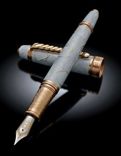 a fountain pen with gold trimmings and an intricate design on the top, sitting in front of a black background