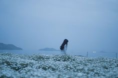 a woman is standing in the water with her back to the camera and she has long hair