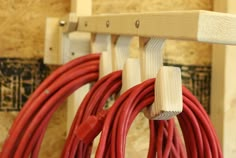 two red cords are connected to wooden hooks