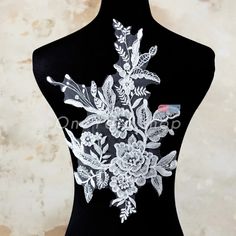 a black mannequin with white flowers and leaves on it's back side